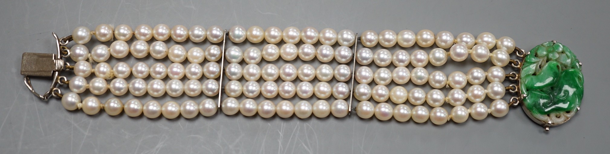 A quintuple strand cultured pearl bracelet, with carved jade set 9ct white metal clasp, 17cm, gross weight 42.5 grams, pearl diameter approx. 5.6mm.